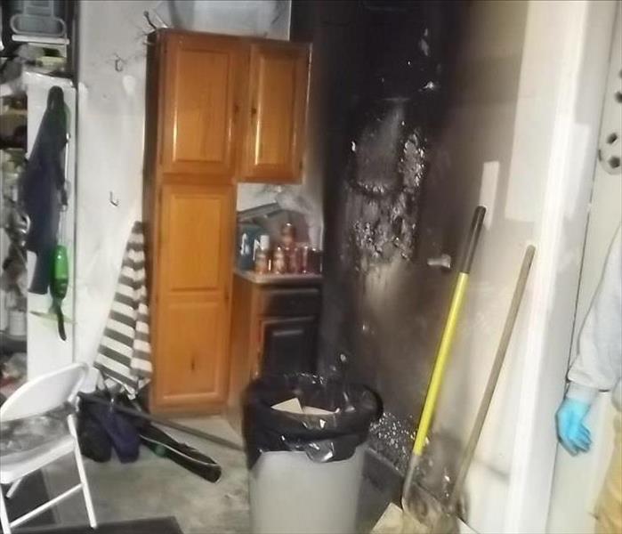 the drywall is burnt on the left side of the door entering the foyer. The garage in the photo has content, is covered in soot